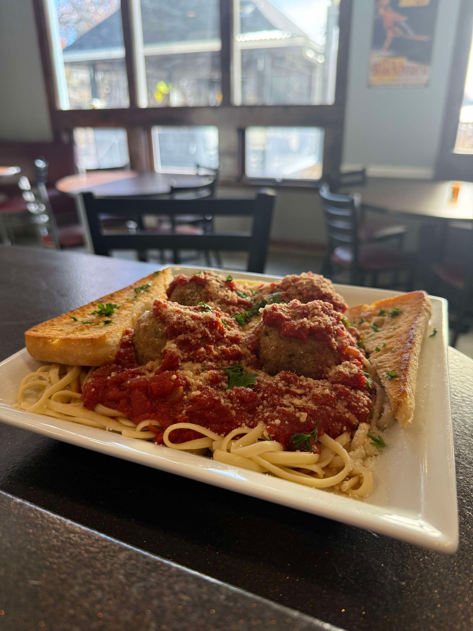 A plate of pasta with meatballs and sauce on a table.