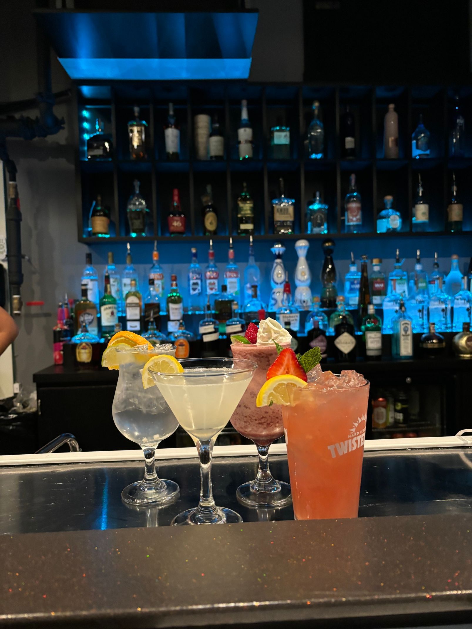 Four drinks are sitting on a bar counter in front of a bar.
