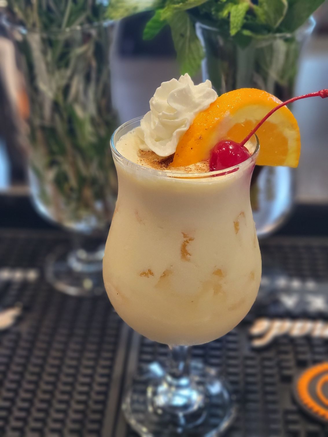 A white drink with whipped cream and a cherry on top