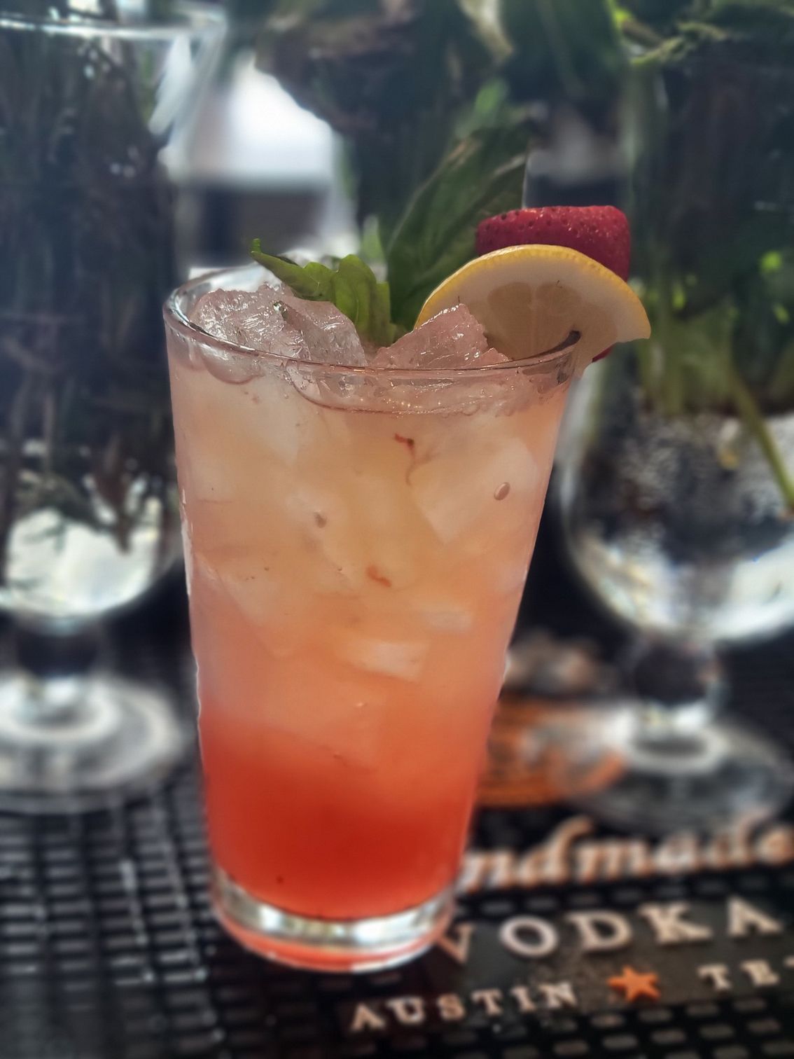 A tall glass filled with a pink drink and a lemon slice
