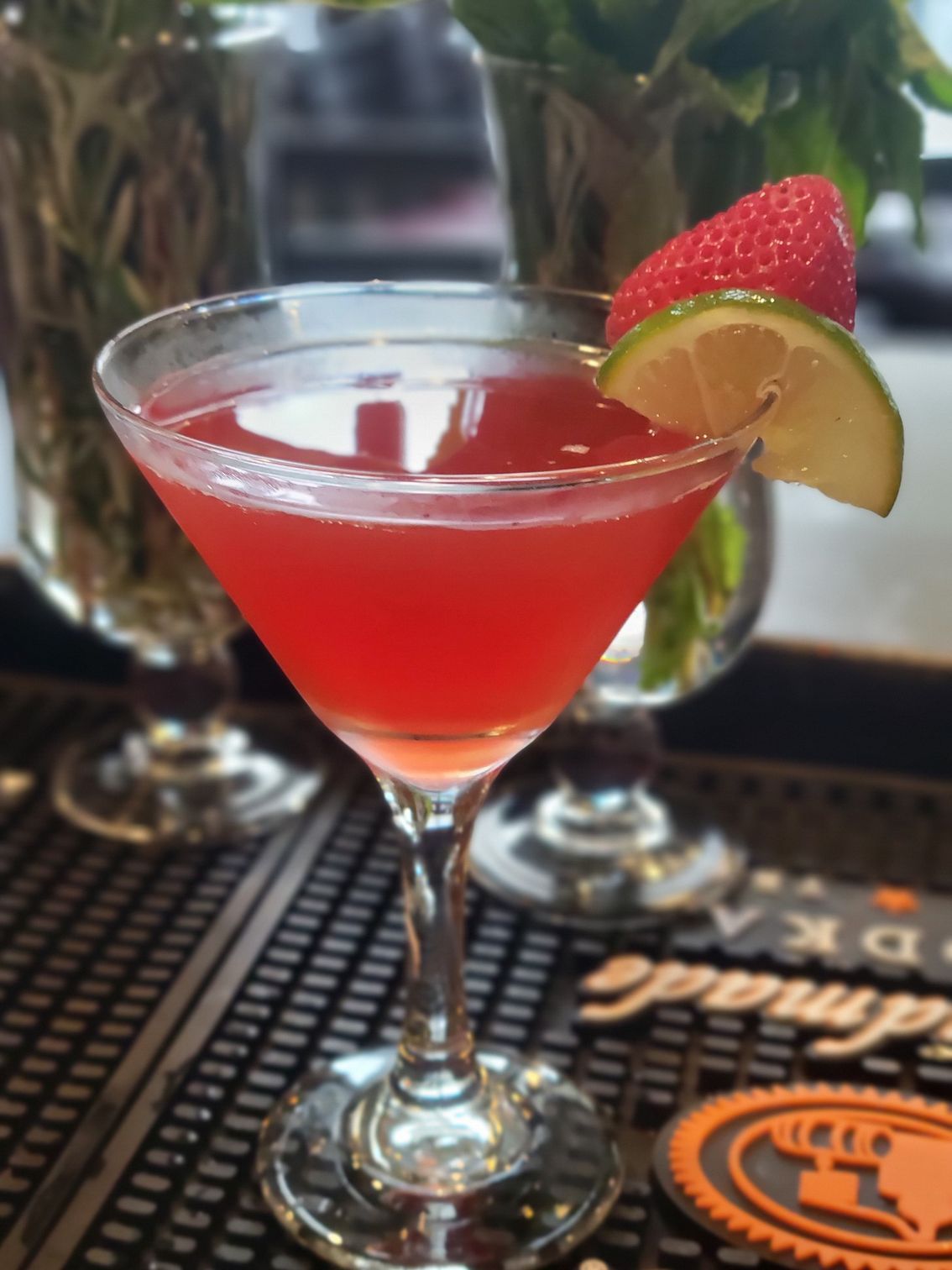 A martini with a strawberry and lime slice