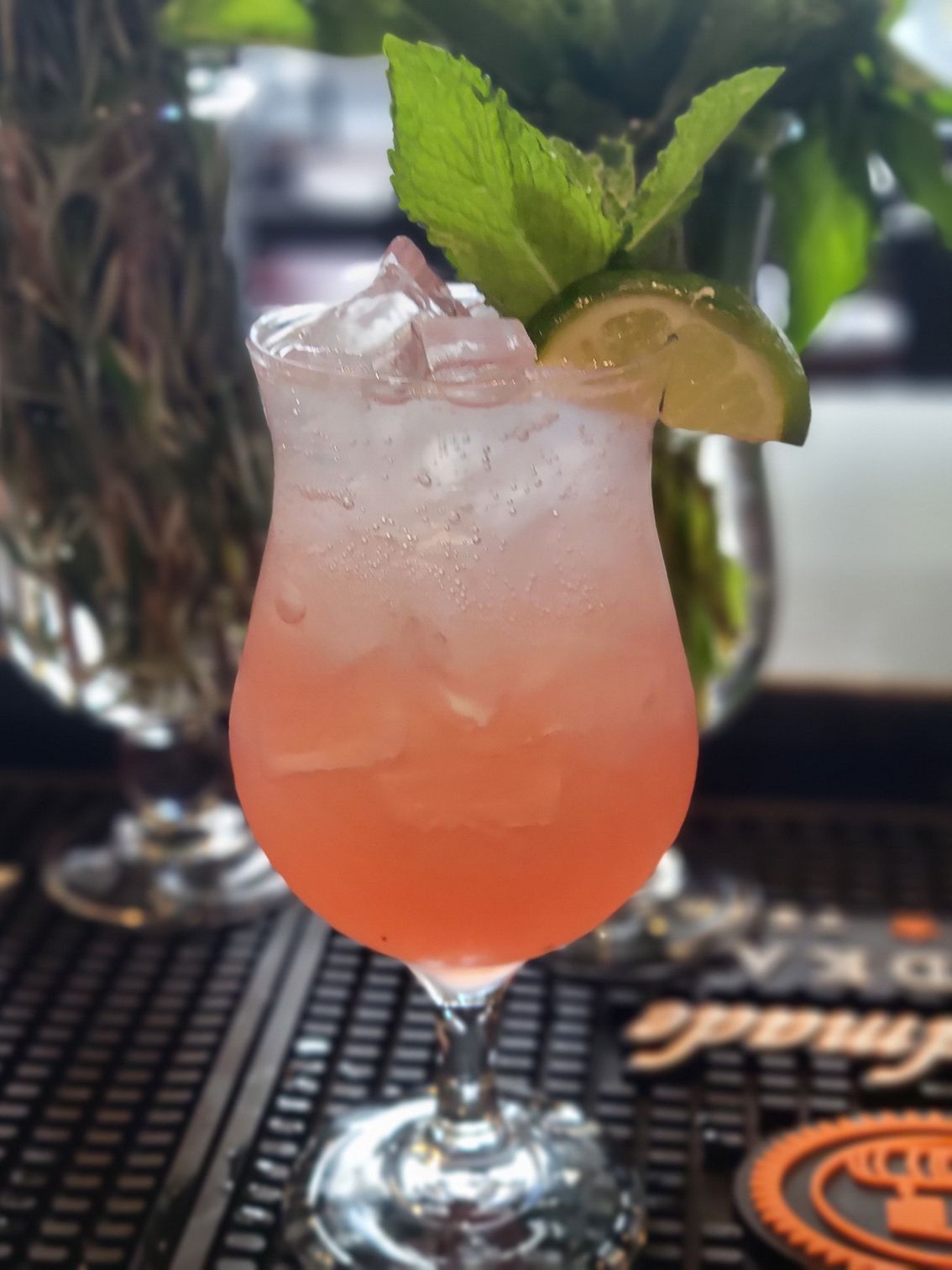 A pink drink in a wine glass with ice and mint leaves