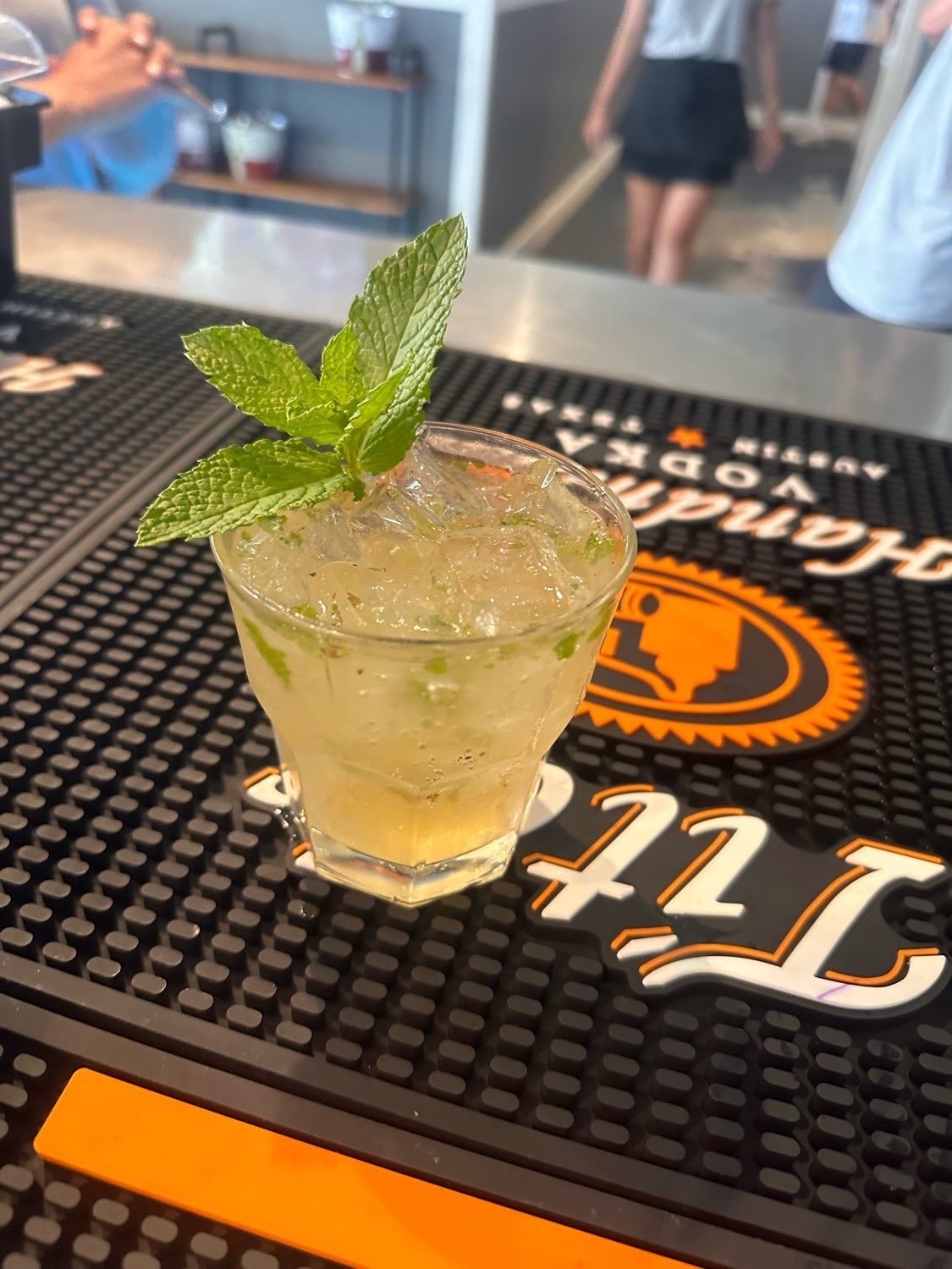 A drink with mint leaves is on a bar mat