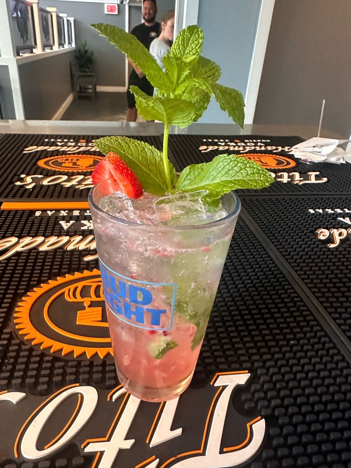 A drink in a bud light glass with strawberries and mint