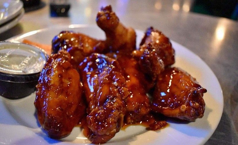 A plate of chicken wings with dipping sauce on a table.