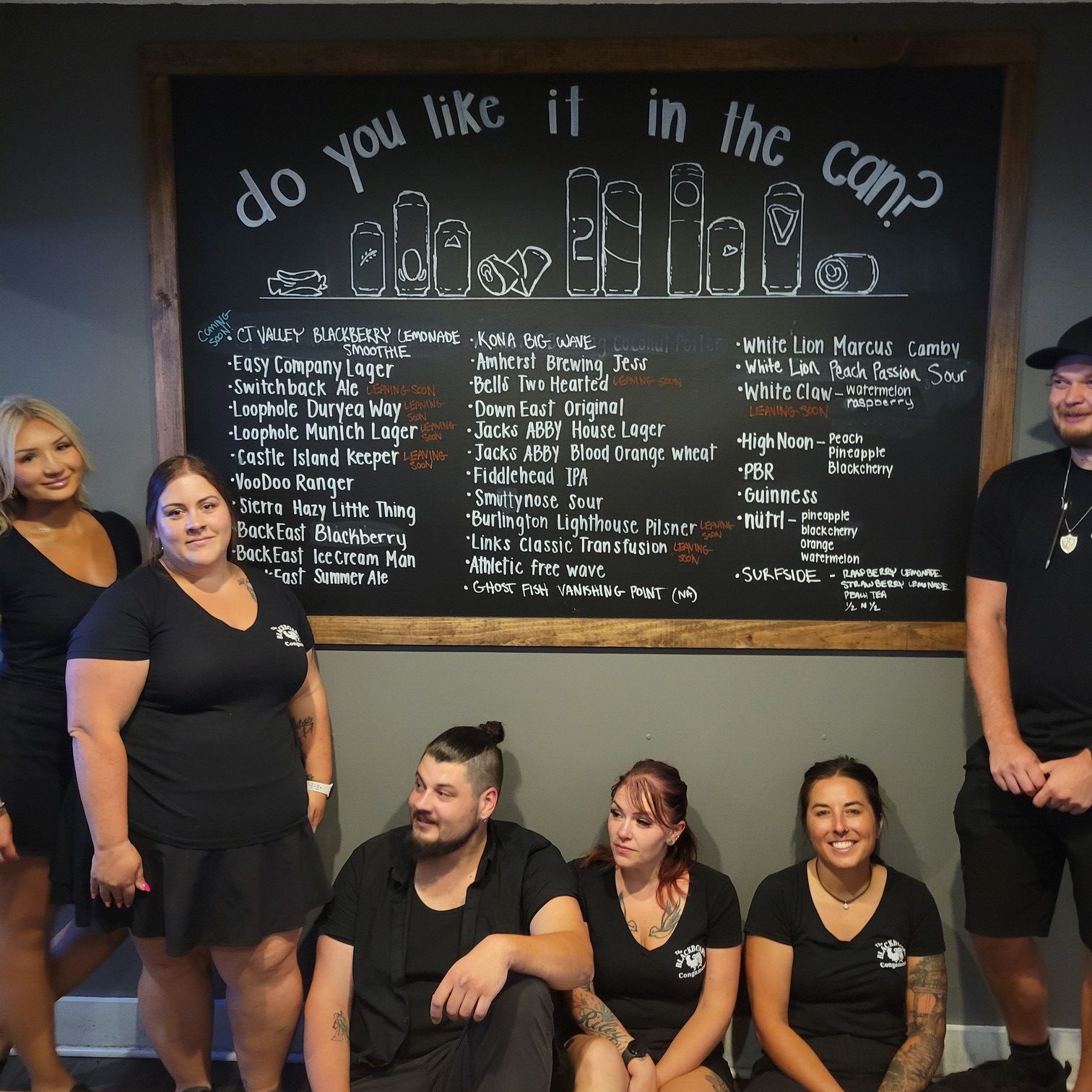 A group of people standing in front of a chalkboard that says do you like it in the can