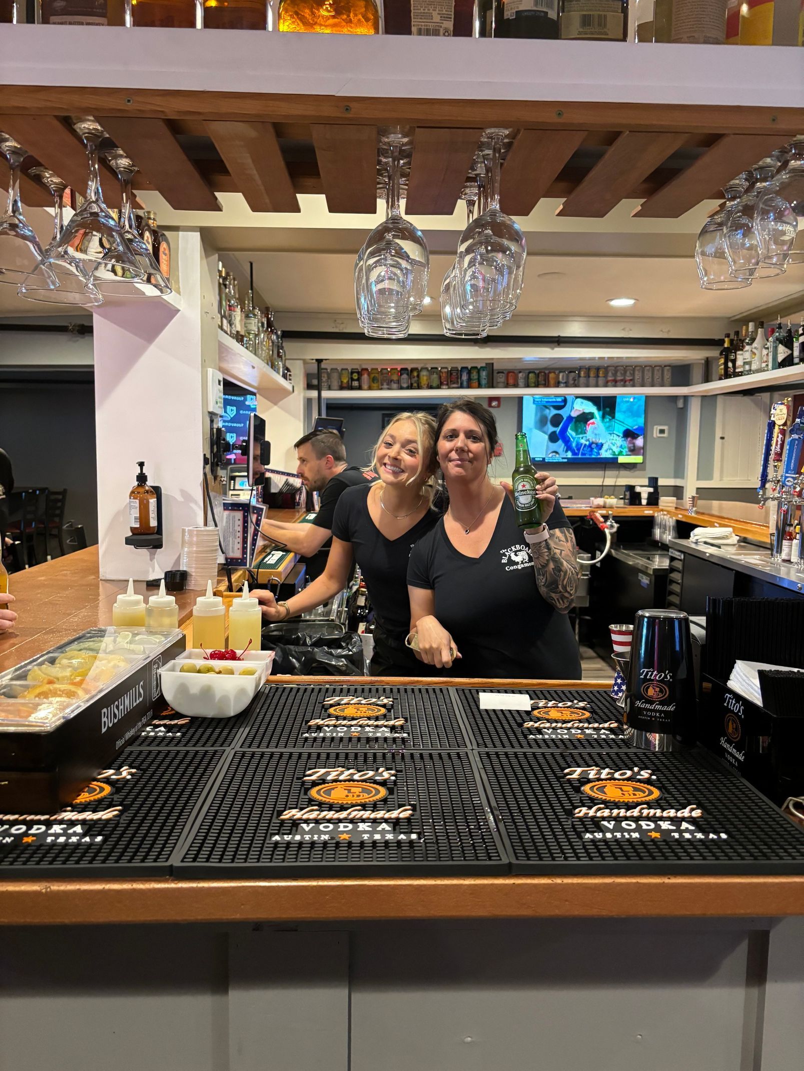Two women are standing behind a bar in a restaurant.