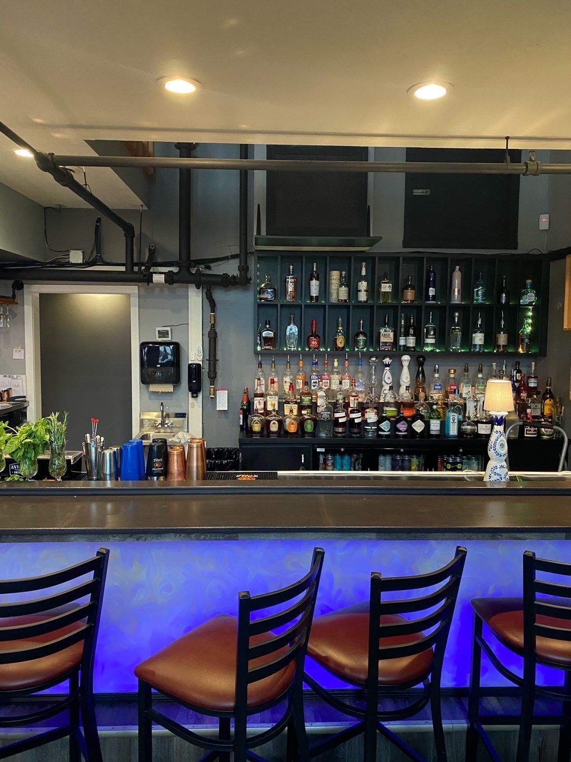 A bar with a lot of bottles on it and a blue light behind it.