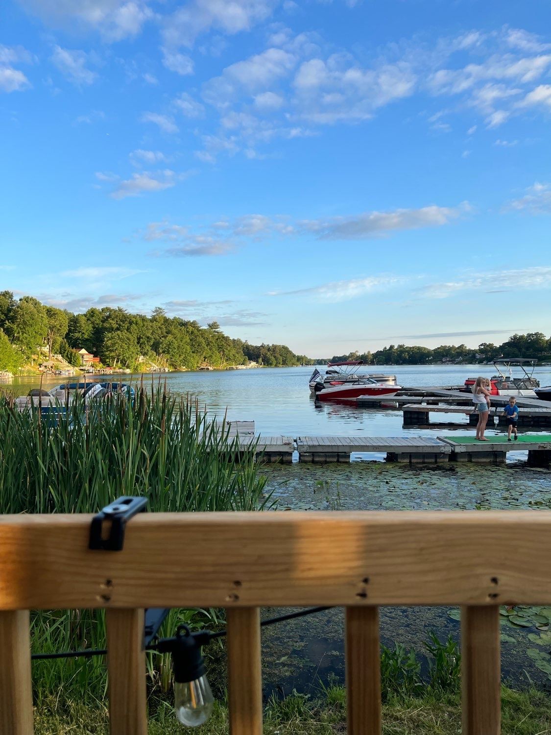 A view of a lake from a deck with boats docked in the water.