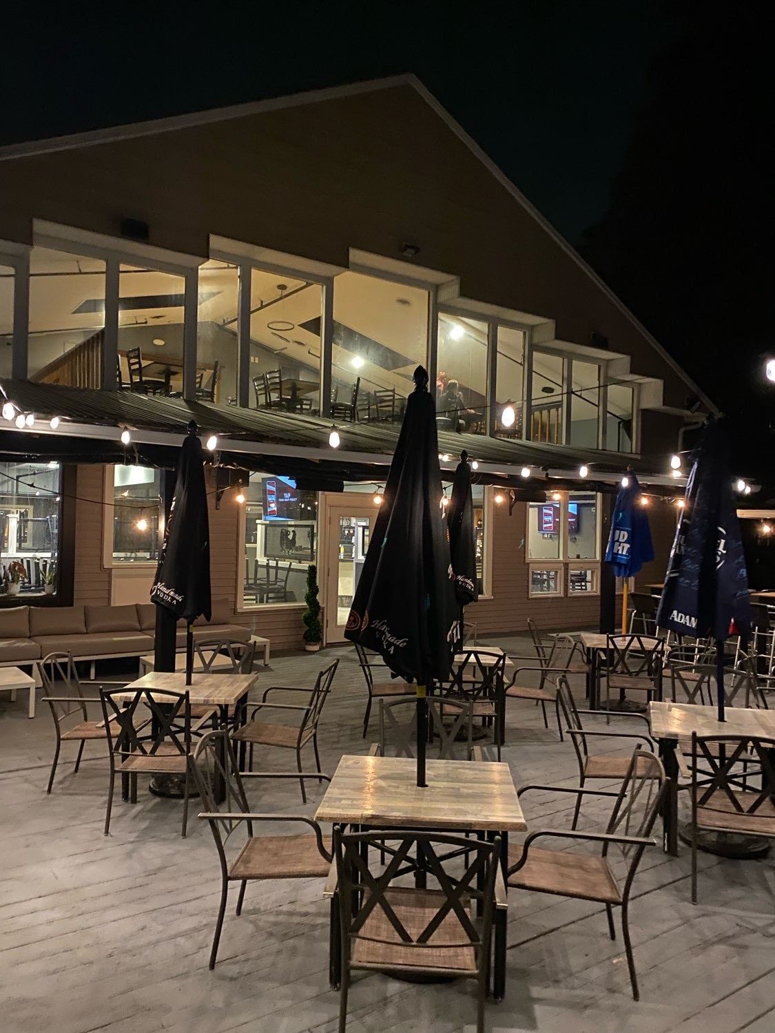 A restaurant with tables and chairs and umbrellas outside at night.