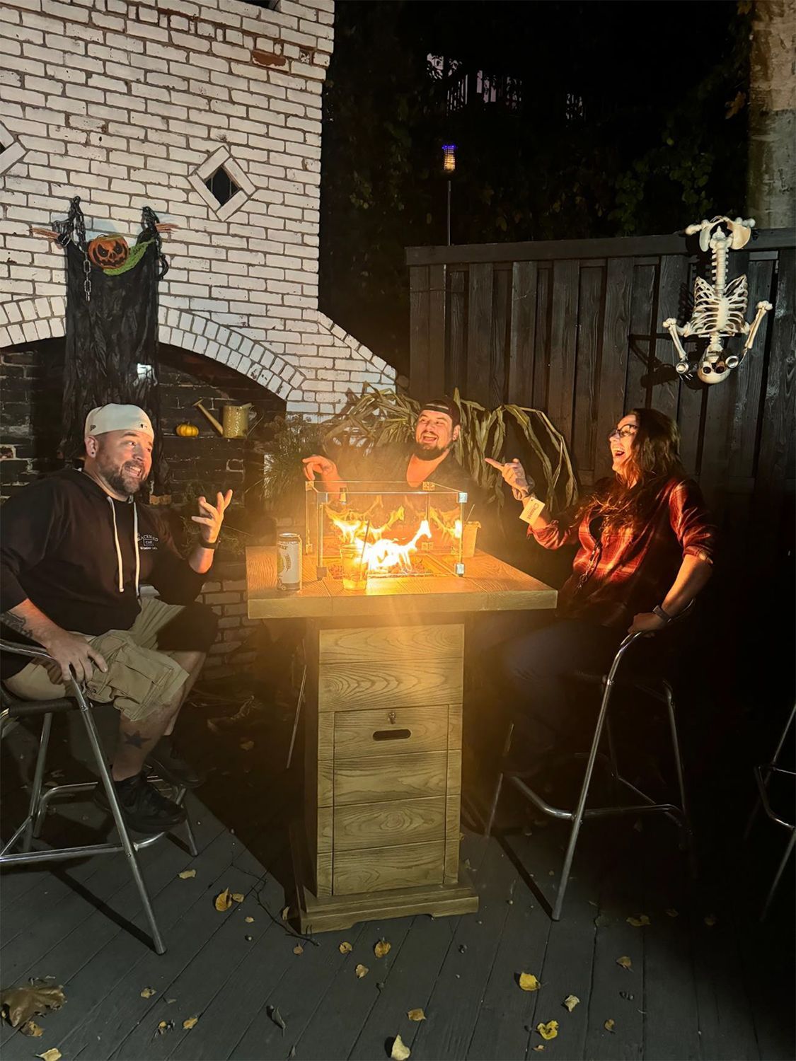 A group of people are sitting around a table with a fire pit.