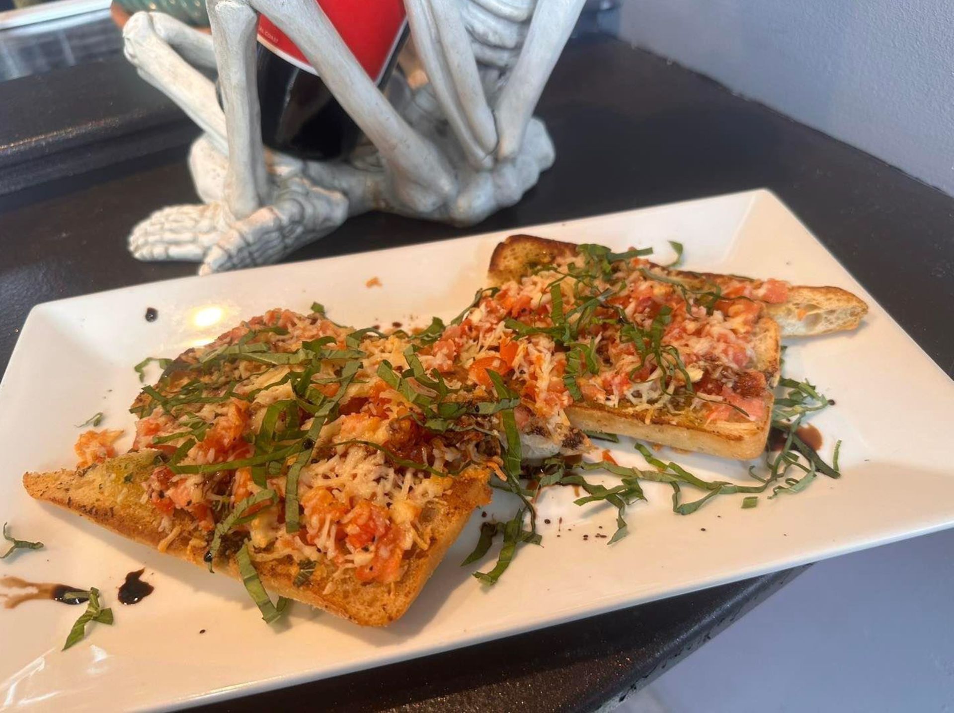 A white plate topped with two slices of pizza next to a skeleton statue.