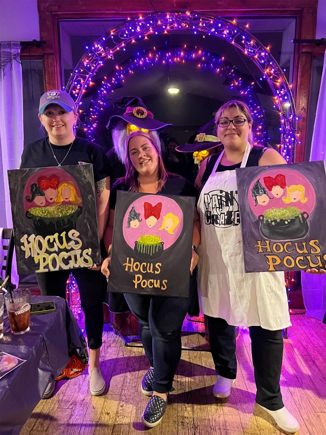 A group of people are posing for a picture with their Halloween paintings.