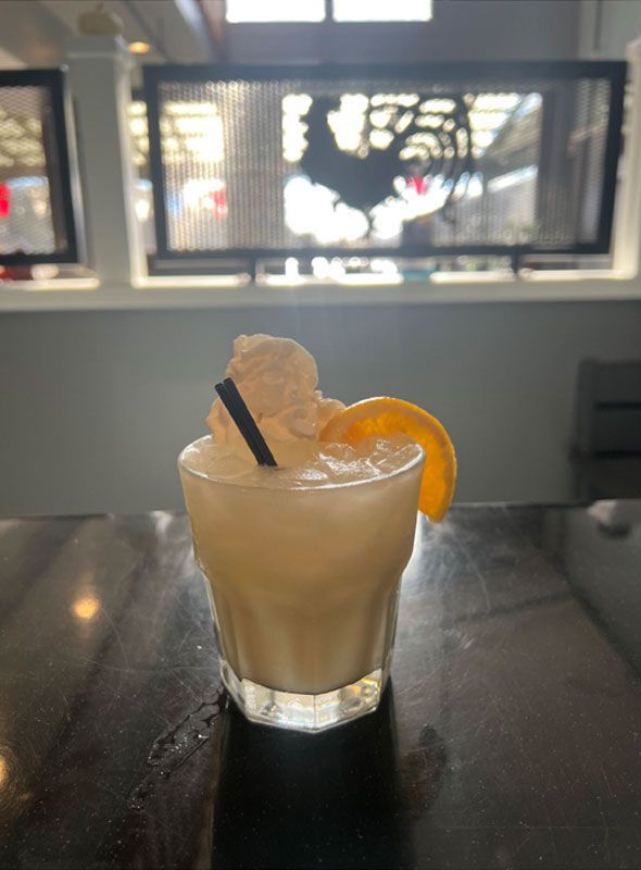 A close up of a drink on a table in front of a window.