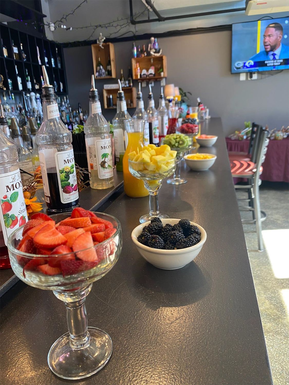 A bar with a bowl of fruit and a bowl of berries on it.