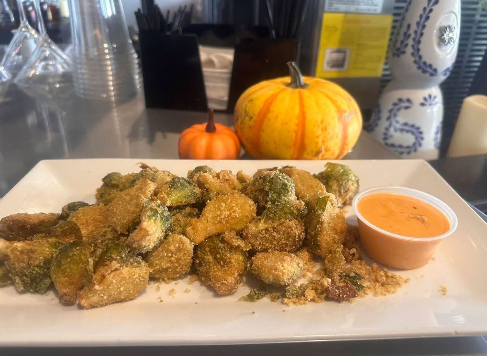A white plate topped with fried brussels sprouts and dipping sauce.