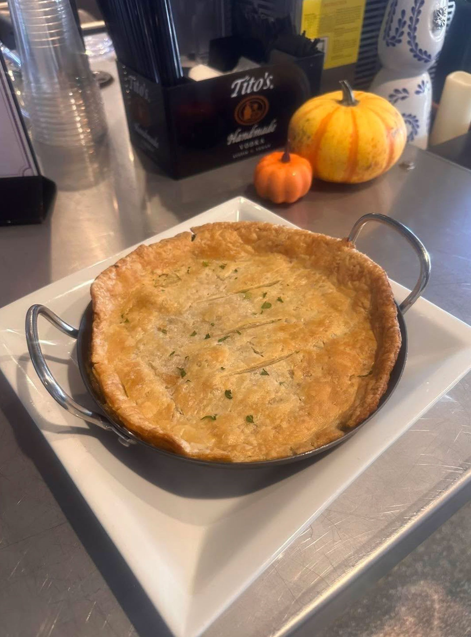 A pot pie is sitting on a white plate on a table.