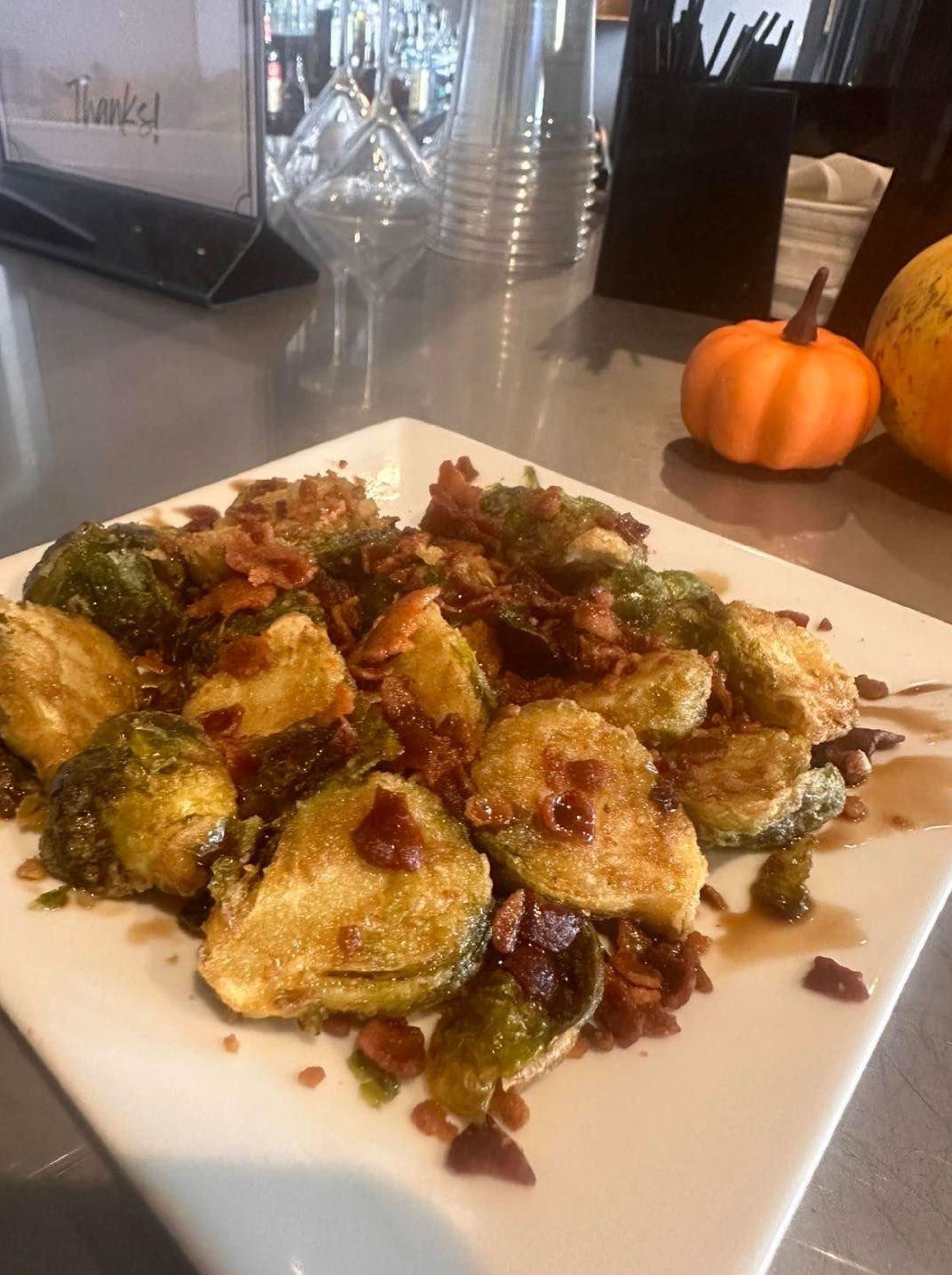 A plate of food with brussels sprouts and bacon on a table.