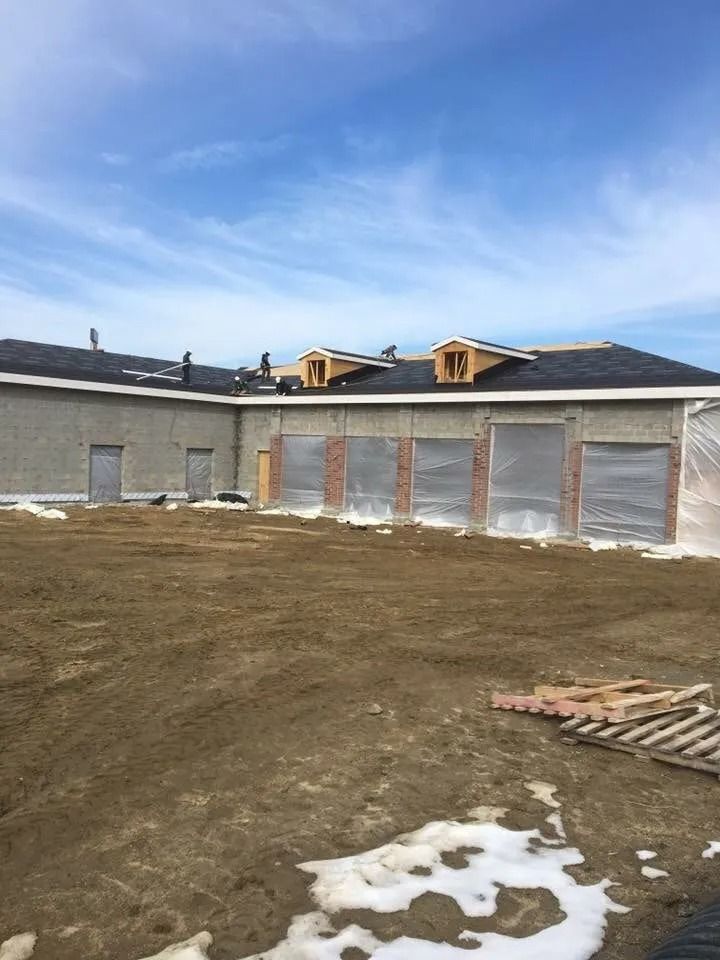 Construction site showing a one-story building under development with unfinished exterior walls and a new roof.