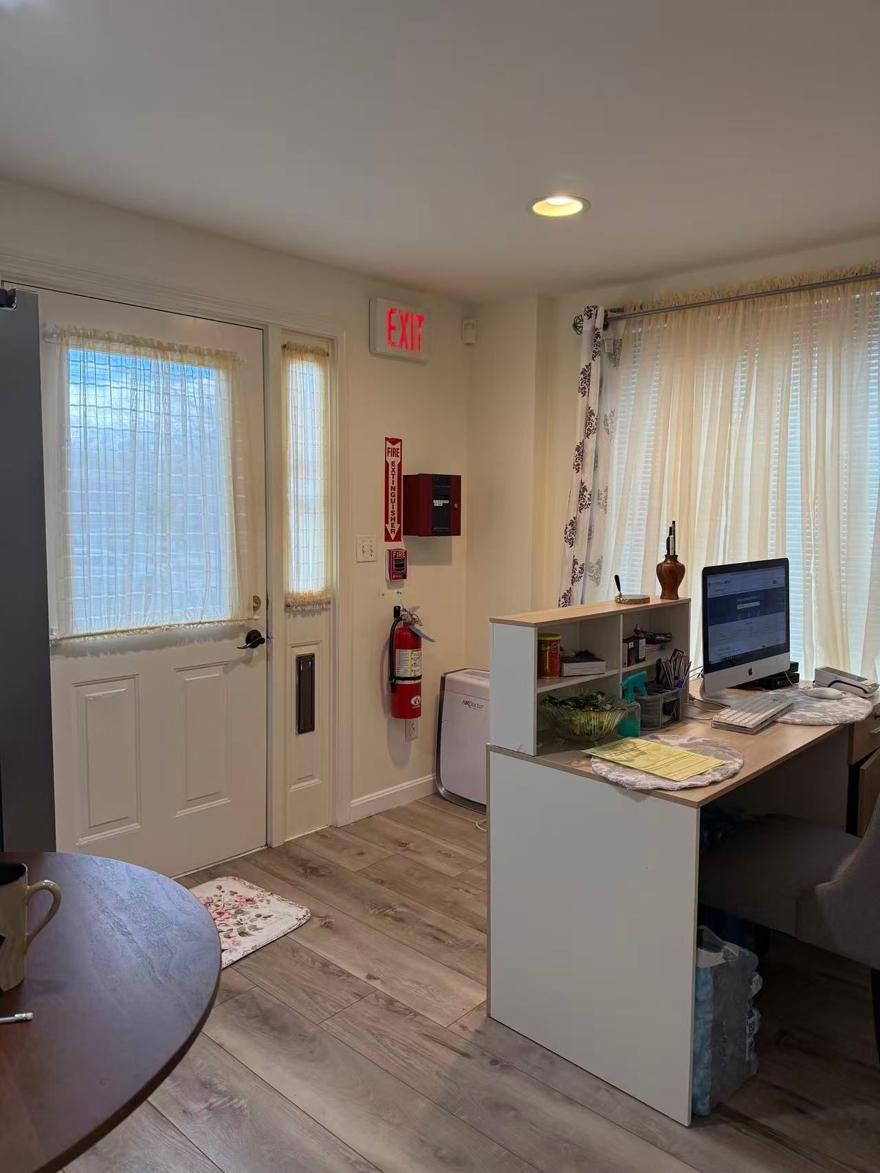 Reception area with desk, computer, door, and fire safety equipment.