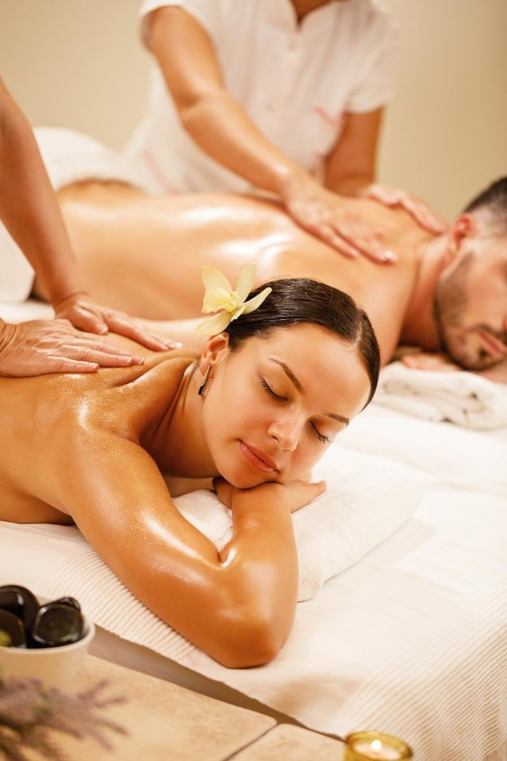 Couple receiving back massages at a spa. They are lying on a massage table.