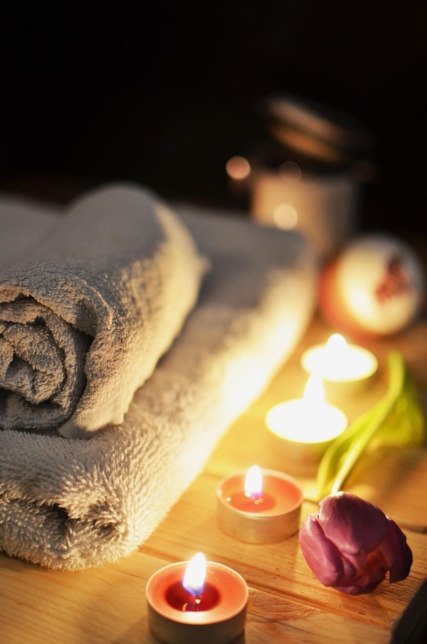 Rolled towels and lit candles, spa setting.