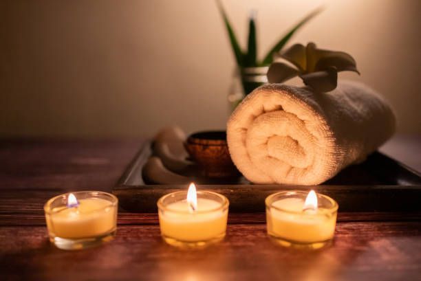 Spa scene: Rolled towel with flower, candles, stones, and aloe, creating a calming ambiance.