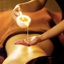 Candle being poured onto a person's hand during a spa treatment.