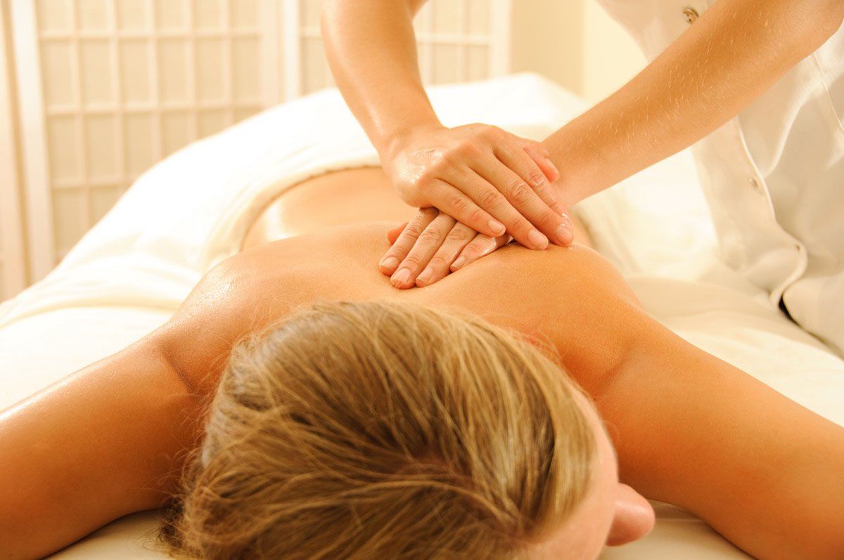 Person receiving back massage on a massage table. Hands of massage therapist visible.