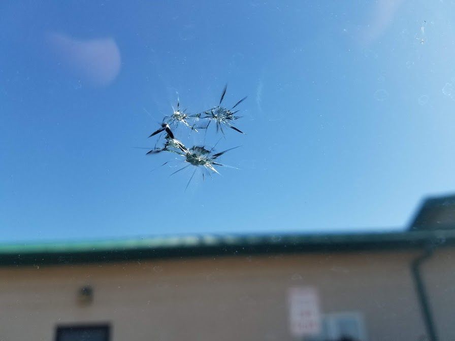 A close up of a broken windshield with a building in the background.