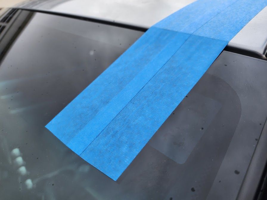 A piece of blue tape is on the windshield of a car