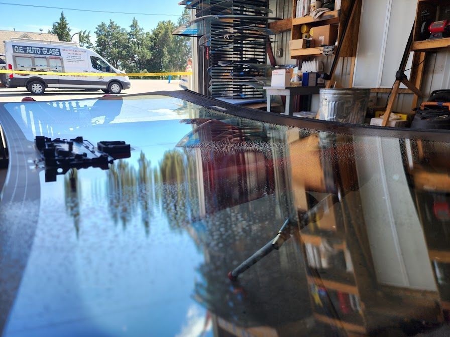 A reflection of a car in a glass table in a garage.