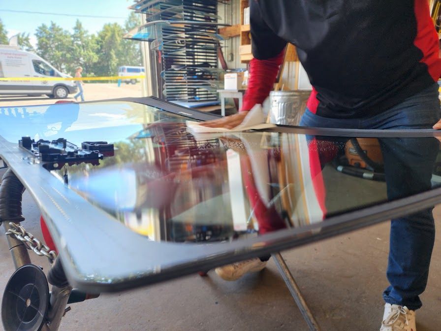 A man is standing next to a large piece of glass.