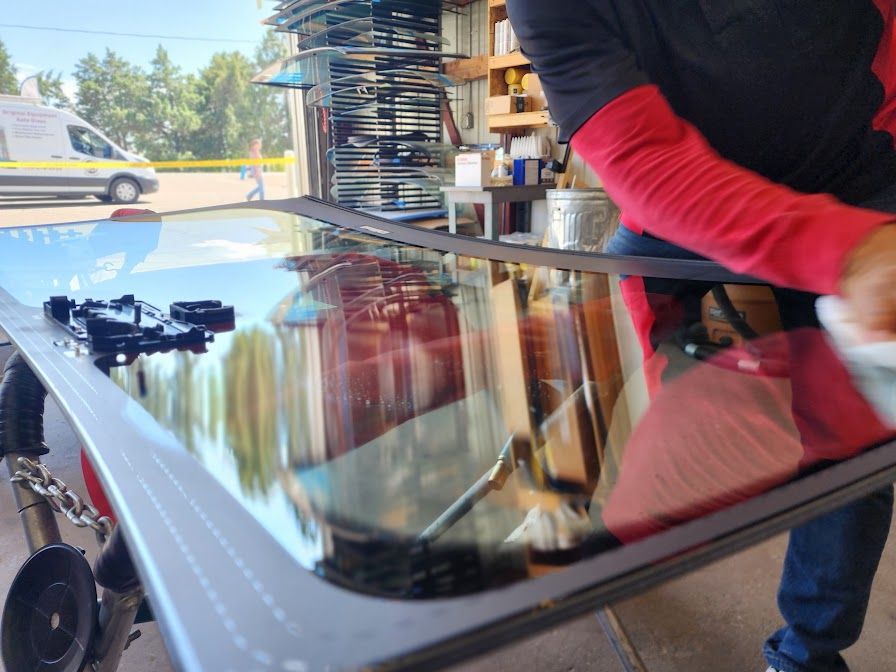 A man is cleaning a car windshield with a cloth
