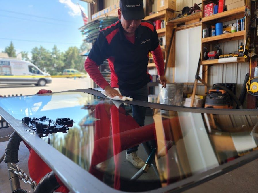 A man is working on a windshield in a garage.
