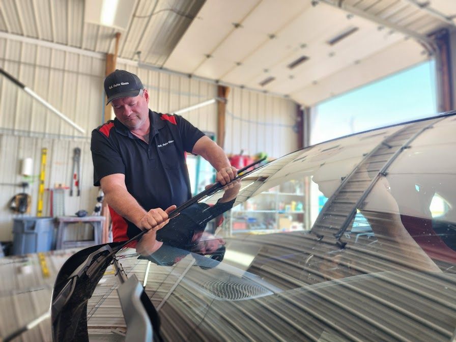 A man is cleaning the windshield of a car in a garage.