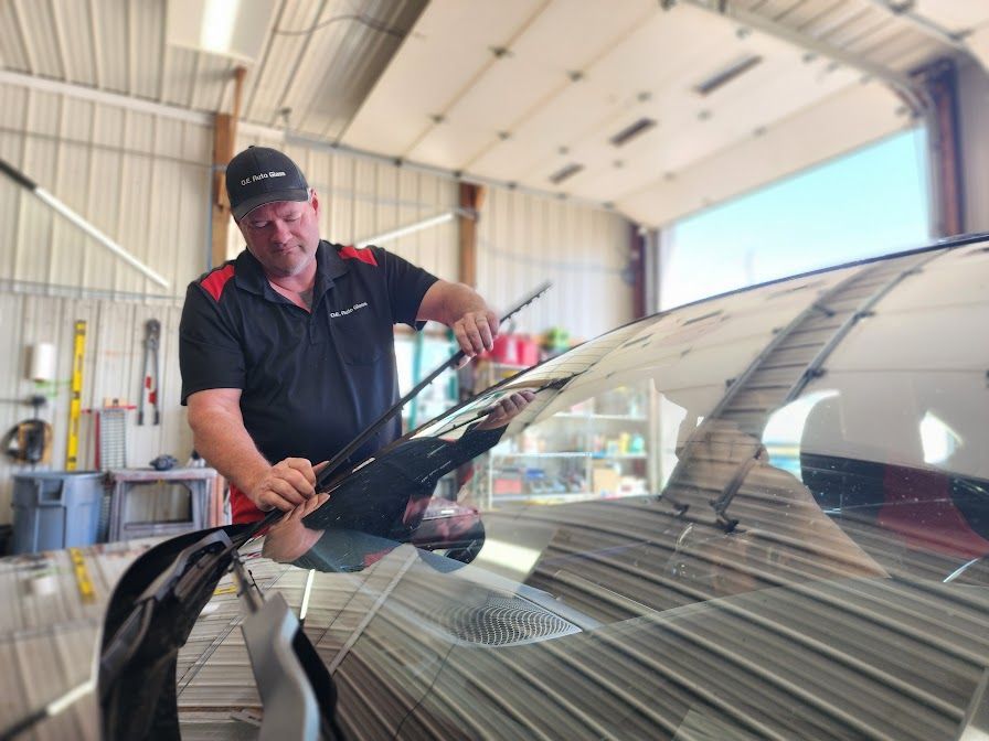 A man is cleaning the windshield of a car in a garage.