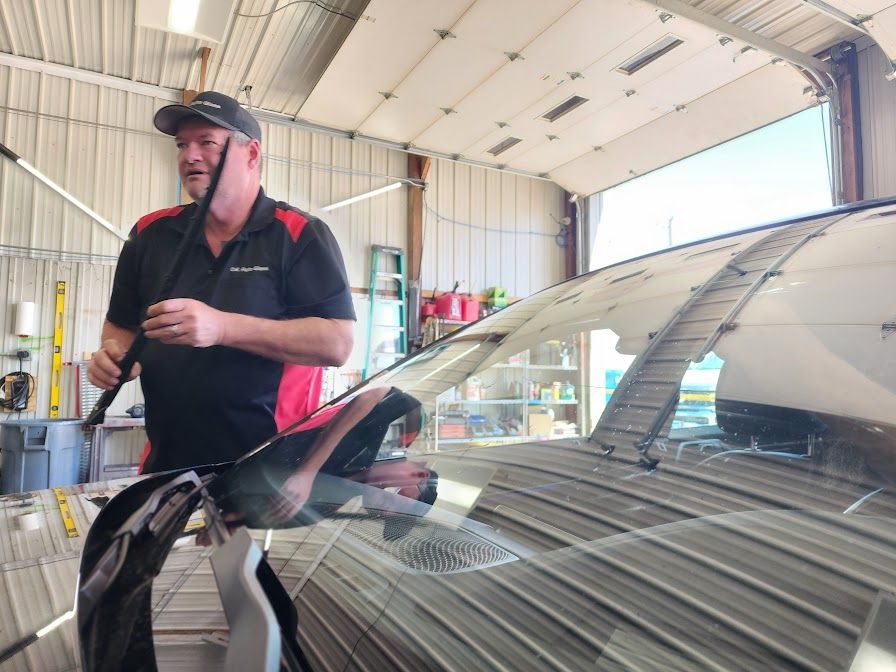 A man is cleaning the windshield of a car in a garage.