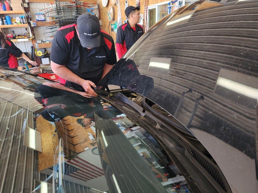 A man is working on a car windshield in a garage.
