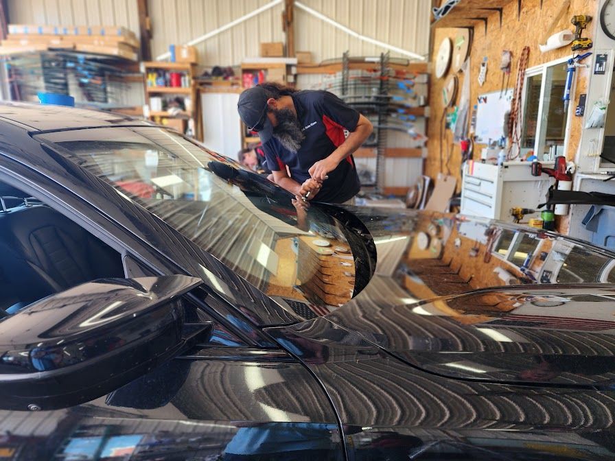 A man is working on a car windshield in a garage.