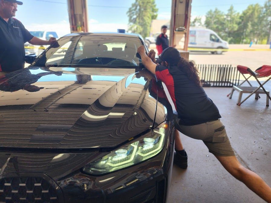 A man is working on a car windshield in a garage.
