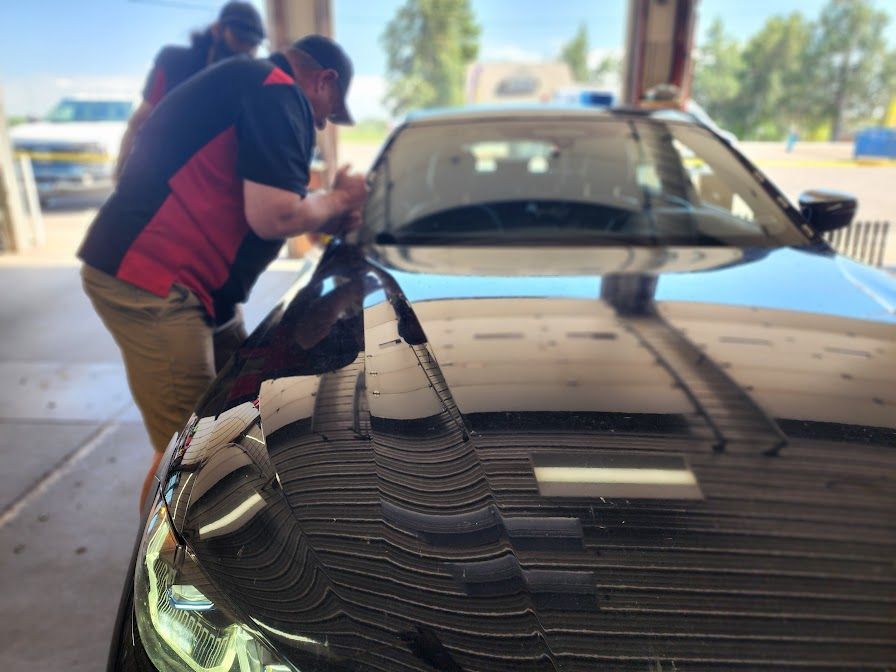 A man is working on the windshield of a car in a garage.