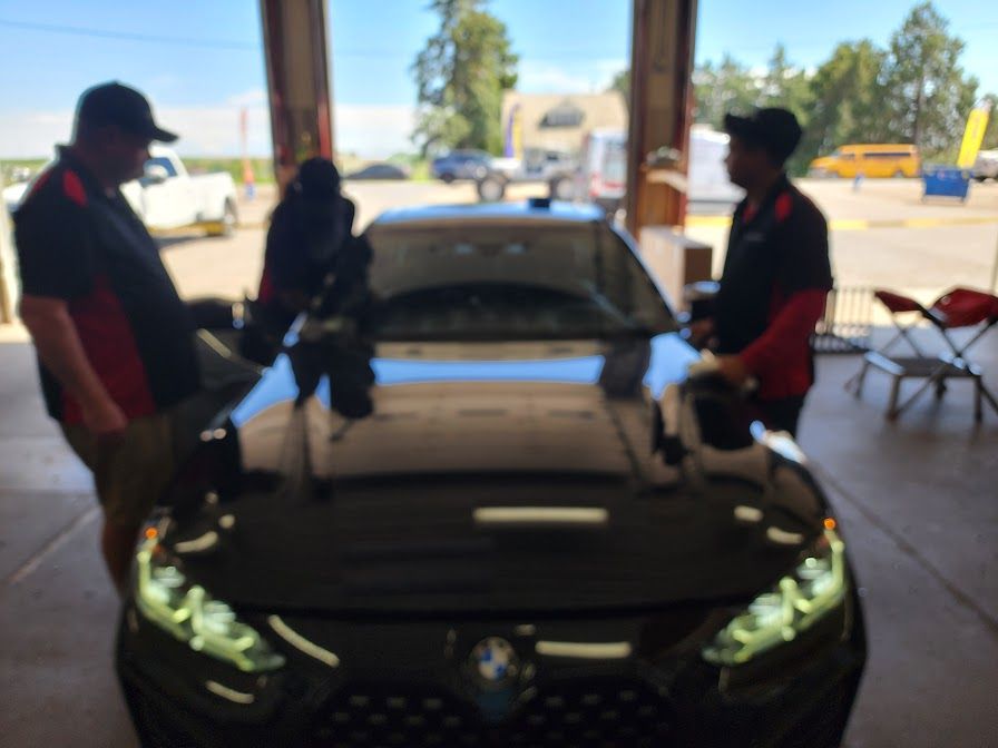 Two men are working on a black car in a garage
