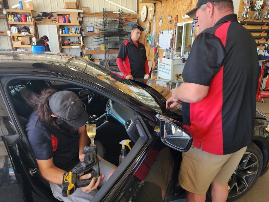 Two men are working on a car in a garage.