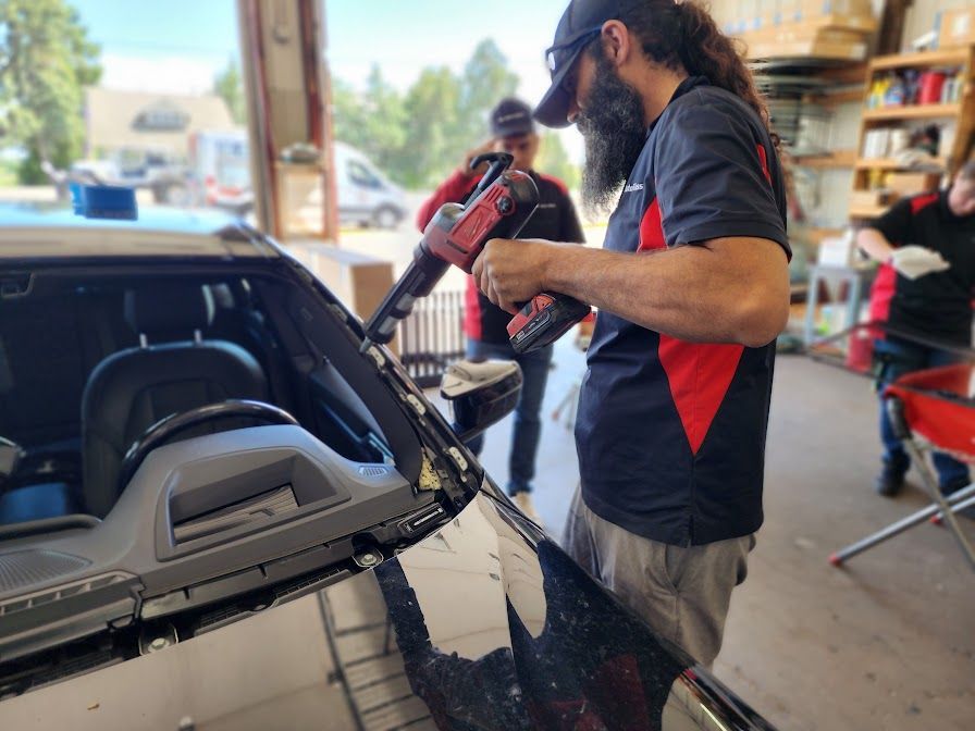 A man is fixing a windshield on a car in a garage.