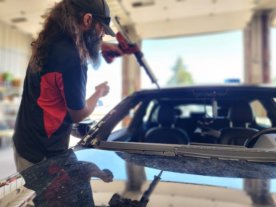 A man is fixing a windshield on a car in a garage.