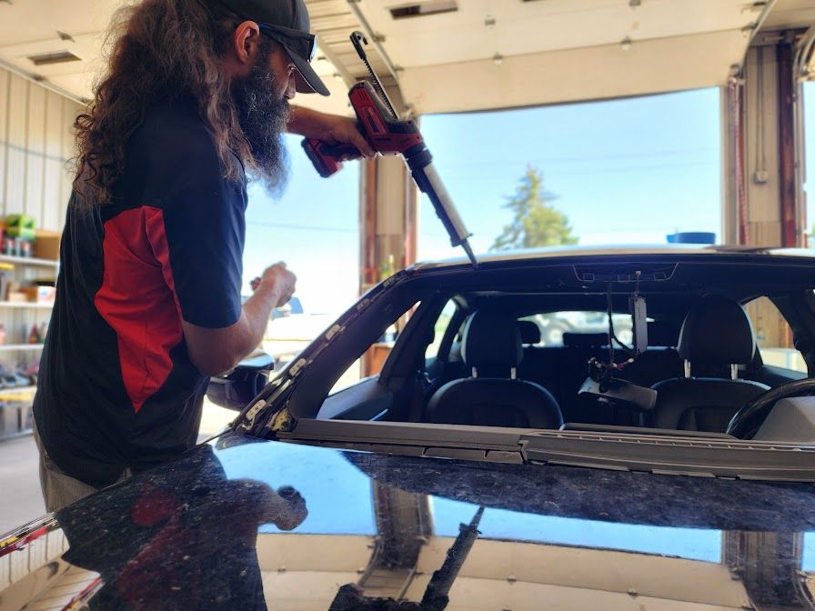 A man is working on a car windshield in a garage