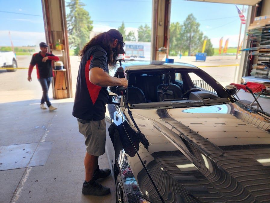 A man is working on a car windshield in a garage.