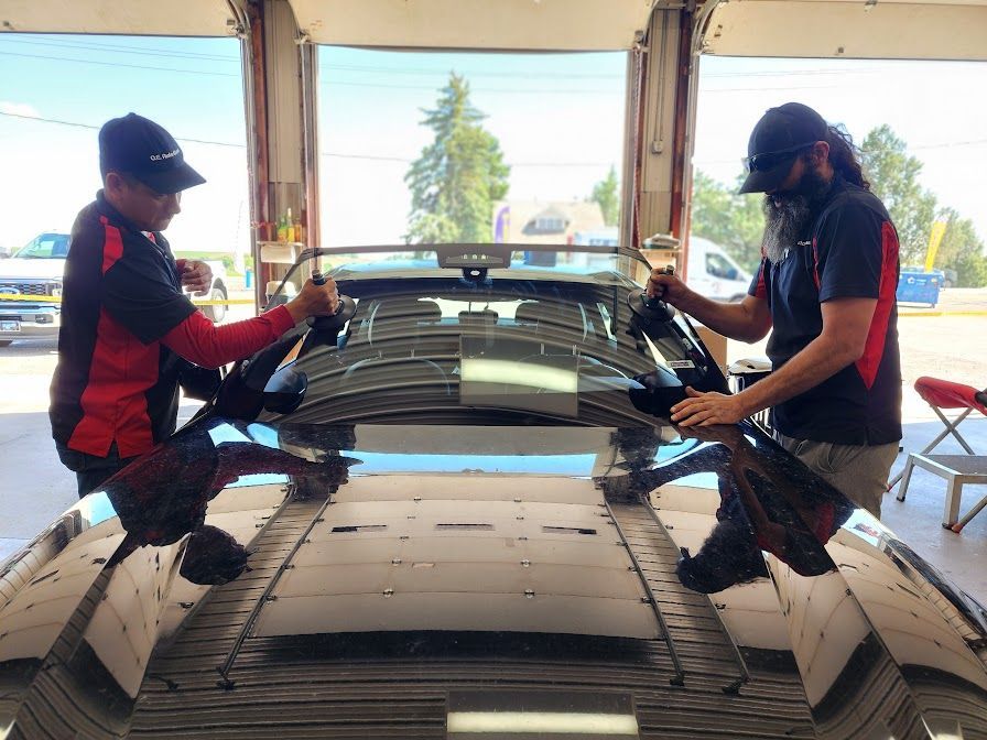 Two men are working on a car in a garage.