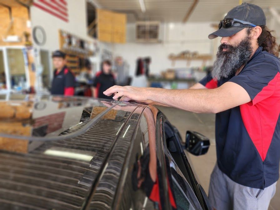 A man with a beard is working on a car in a garage